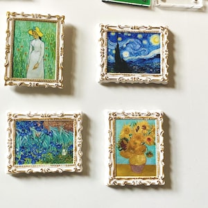 May include: Miniature framed art prints featuring famous paintings. The collection includes Van Gogh's "Starry Night" and "Sunflowers", along with other impressionist art pieces. Each frame has a white and gold ornate design.