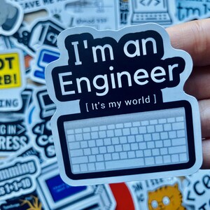 Może przedstawiać: Czarno-biała naklejka z tekstem "I'm an Engineer [It's my world]" i grafiką klawiatury. Naklejka znajduje się na dłoni.