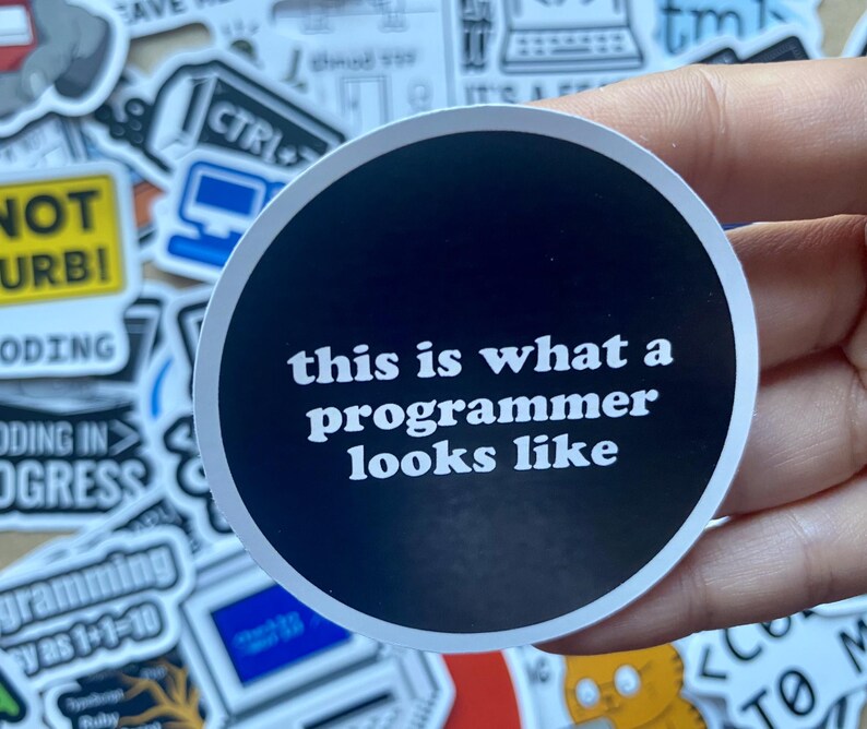 Może przedstawiać: Czarno-biała naklejka z tekstem "this is what a programmer looks like" na białym tle.