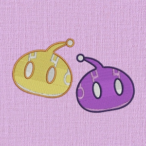 May include: Two embroidered patches in the shape of alien creatures. The first patch is yellow with white eyes and the second patch is purple with white eyes.