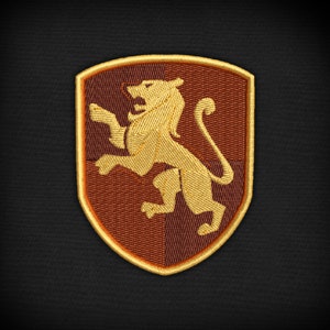 Peut inclure: Un écusson brodé représentant un lion dans un bouclier, avec des couleurs brunes et dorées.