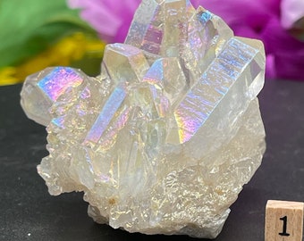 May include: A cluster of iridescent white quartz crystals with a rainbow sheen. The crystals are arranged in a cluster and have a natural, rough texture.