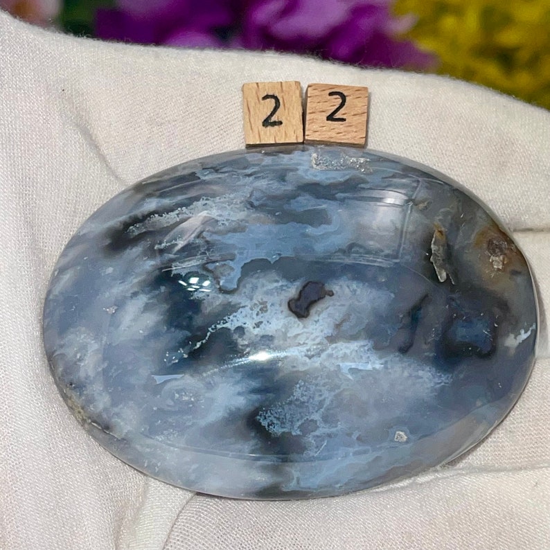 K&ouml;nnte beinhalten: Ein polierter, ovaler blauer Achat-Stein mit wei&szlig;en und schwarzen wirbelnden Mustern. Der Stein hat einen Durchmesser von etwa 5 cm.