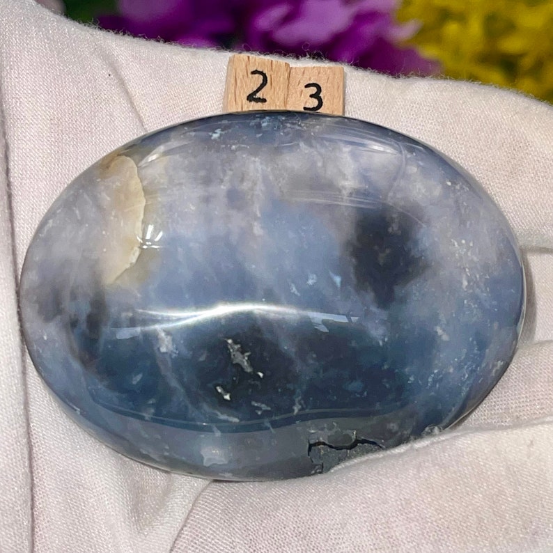K&ouml;nnte beinhalten: Ein glatter, ovaler blauer Achat-Stein mit wei&szlig;en und grauen Markierungen. Der Stein hat eine polierte Oberfl&auml;che und ist etwa 5,8 cm lang.