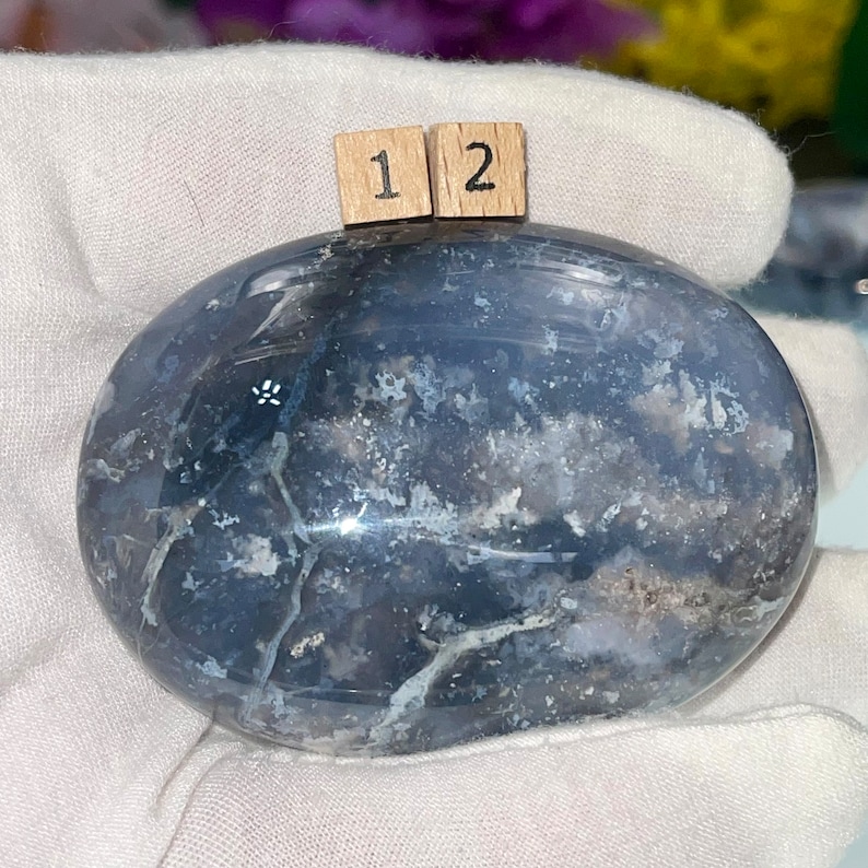 May include: A smooth, oval-shaped, polished blue agate stone with white and gray markings. The stone is approximately 2 inches in diameter.