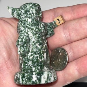 Detailed crystal carvings: jadeite master and green jasper alien child. Metaphysical decor, conversation starters, and collector's items. Calming stone art.