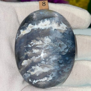 May include: A smooth, oval-shaped polished stone with a swirling pattern of white, gray, and blue.