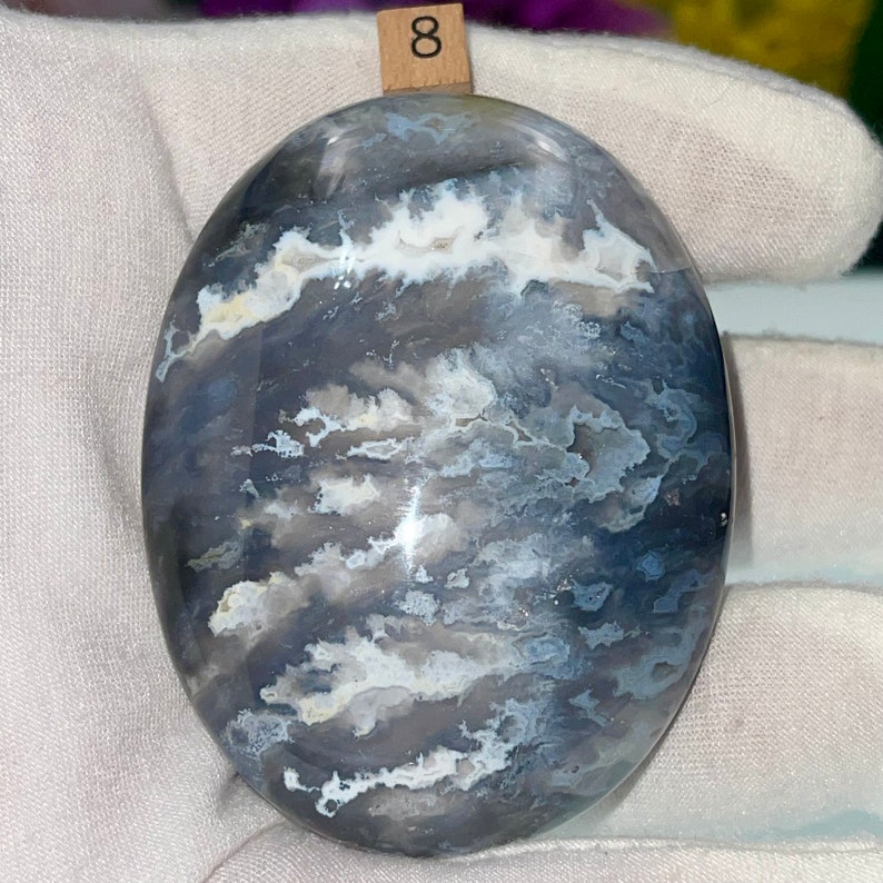 May include: A smooth, oval-shaped polished stone with a swirling pattern of white, gray, and blue.