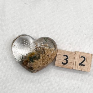 Può includere: Un cristallo trasparente a forma di cuore con inclusioni marroni e dorate. Il cristallo misura circa 3,2 cm.