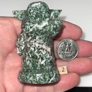 Intricate jadeite mentor and green dot jasper alien child carvings. Unique collector's items, spiritual growth aids, and pop culture-inspired crystal art.