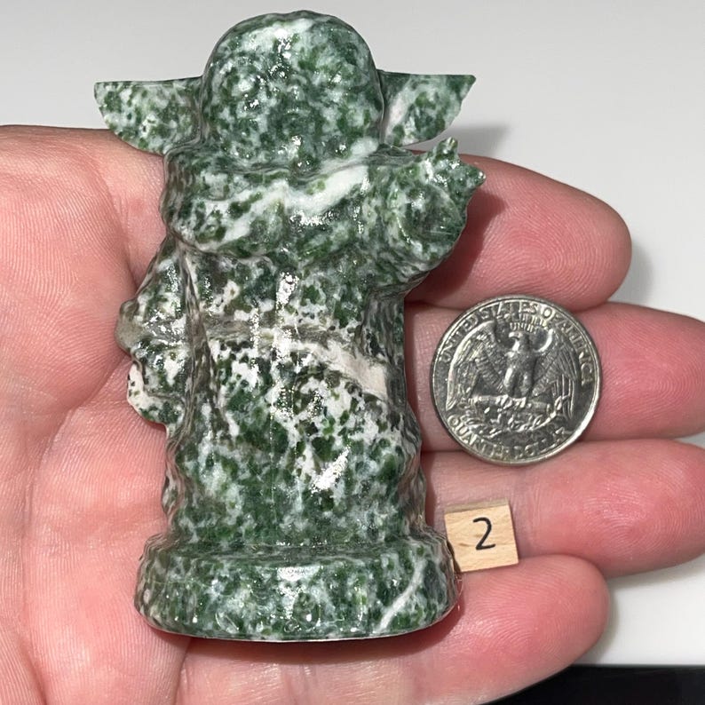 Intricate jadeite mentor and green dot jasper alien child carvings. Unique collector's items, spiritual growth aids, and pop culture-inspired crystal art.