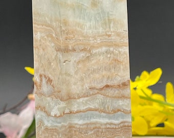 May include: A light green and brown banded crystal point, also known as a tower, with a pointed top and a flat base. The crystal is approximately 8 inches tall.