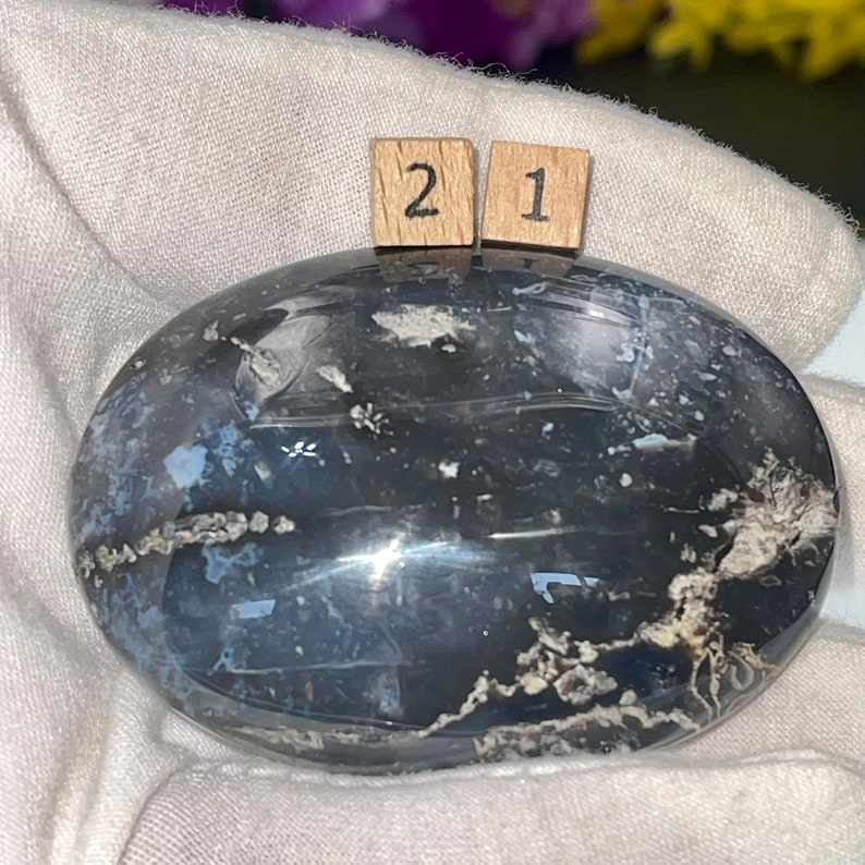 K&ouml;nnte beinhalten: Ein glatter, ovaler schwarzer und wei&szlig;er Achat-Stein mit polierter Oberfl&auml;che. Der Stein hat ein wirbelndes Muster aus Wei&szlig; und Schwarz.