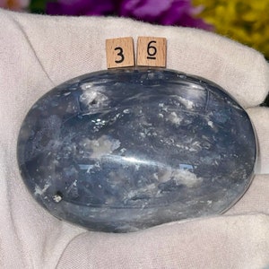 May include: A smooth, oval-shaped blue agate stone with white and gray markings. The stone is approximately 3.6 inches long.