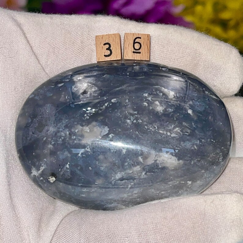 May include: A smooth, oval-shaped blue agate stone with white and gray markings. The stone is approximately 3.6 inches long.