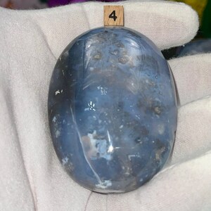 May include: A smooth, oval-shaped blue agate stone with white and gray markings. The stone is labeled with the number "4".