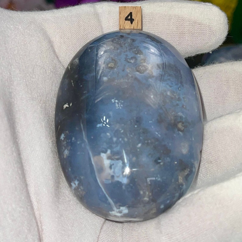 May include: A smooth, oval-shaped blue agate stone with white and gray markings. The stone is labeled with the number "4".