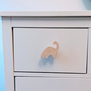 Peut inclure: Commode blanche avec une poignée de tiroir en forme de dinosaure en bois.