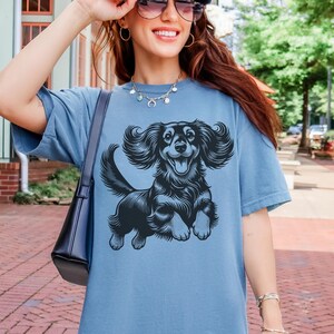 Comfort colors tshirt featuring a black illustration of a long haired dachshund dog jumping up.
