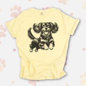 Comfort colors premium shirt featuring a black illustration of a long haired dachshund dog jumping up.