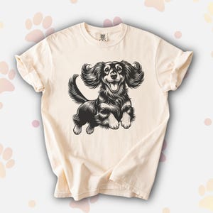 Comfort colors premium shirt featuring a black illustration of a long haired dachshund dog jumping up.