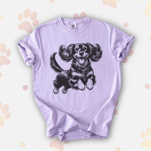 Comfort colors premium shirt featuring a black illustration of a long haired dachshund dog jumping up.