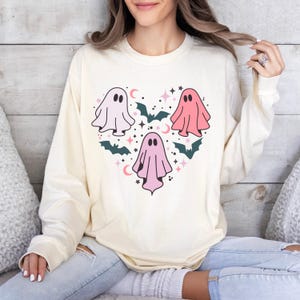 T-shirt with a heart-shaped design featuring three ghosts in pink and white with bats and stars.