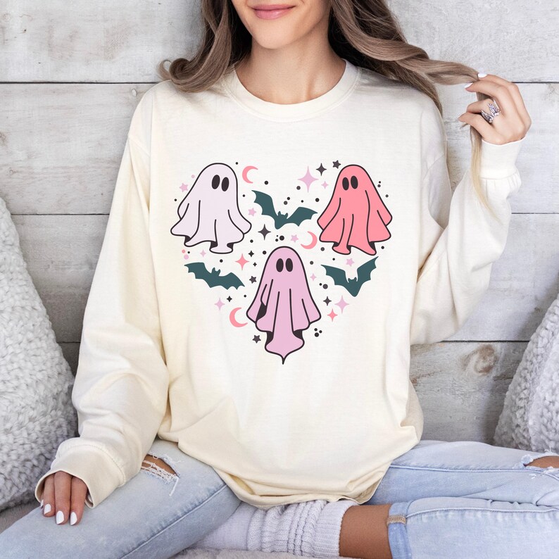 T-shirt with a heart-shaped design featuring three ghosts in pink and white with bats and stars.