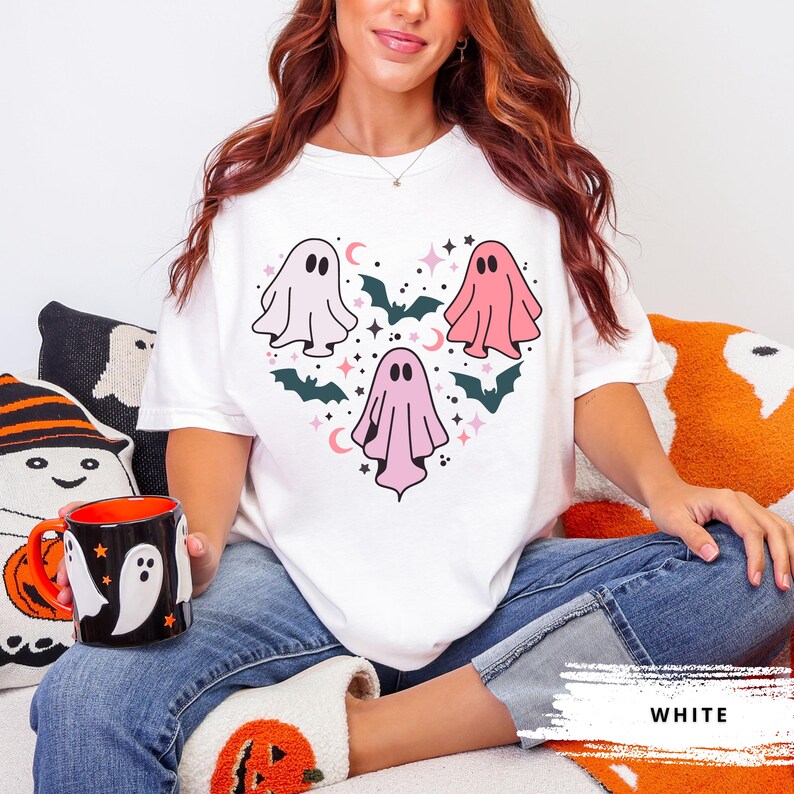 T-shirt with a heart-shaped design featuring three ghosts in pink and white with bats and stars.