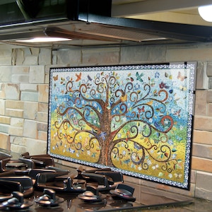 Puede incluir: Un salpicadero de azulejos de mosaico de colores con un árbol estilizado con ramas en espiral y pájaros. El salpicadero está instalado sobre una estufa de gas en una cocina.