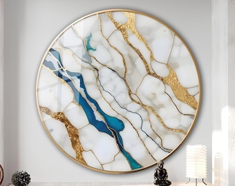 May include: A circular wall art piece with a gold frame. The artwork has a white marble design with gold and blue accents. The gold accents resemble veins or cracks, and the blue creates a river-like pattern.