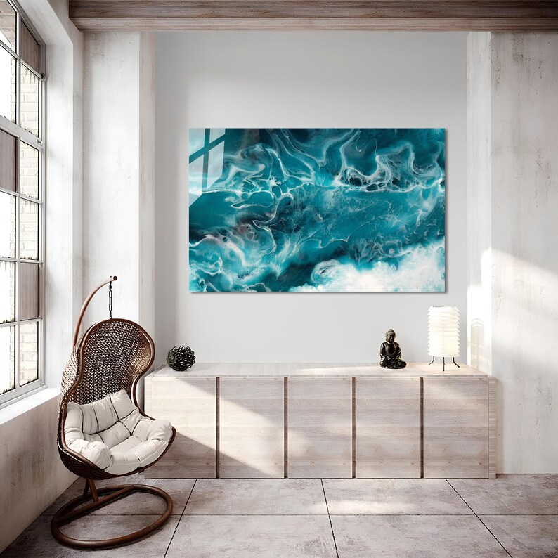 Puede incluir: Arte de pared abstracto con pintura azul y blanca en espiral, que recuerda a las olas del oc&eacute;ano. La obra de arte se muestra en un ambiente de sala de estar moderno con una silla colgante y un gabinete de madera.