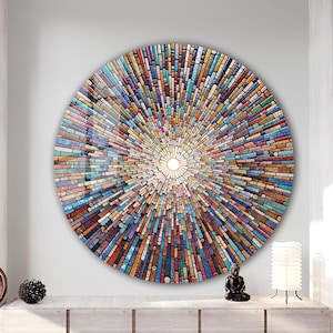 May include: A large, round wall art piece with a mosaic design. The artwork features a central white circle, with colorful rectangular tiles radiating outwards. The tiles are in shades of blue, orange, red, and brown, creating a sunburst effect.