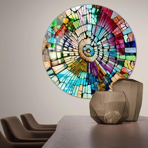 Op de afbeelding: Een kleurrijk cirkelvormig wandkunstwerk met een moza&iuml;ekontwerp. De moza&iuml;ek is gemaakt van kleine, kleurrijke vierkanten en rechthoeken. Het ontwerp is een spiraal die in het midden begint en naar buiten uitbreidt. De wandkunst hangt aan een lichtgrijze muur.