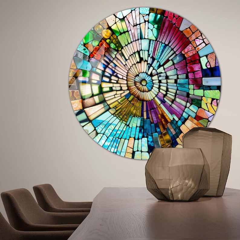 Op de afbeelding: Een kleurrijk cirkelvormig wandkunstwerk met een moza&iuml;ekontwerp. De moza&iuml;ek is gemaakt van kleine, kleurrijke vierkanten en rechthoeken. Het ontwerp is een spiraal die in het midden begint en naar buiten uitbreidt. De wandkunst hangt aan een lichtgrijze muur.