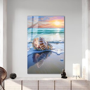 May include: A seashell with brown and white stripes sits on a sandy beach with foamy waves and a blue sky with a sunset in the background.