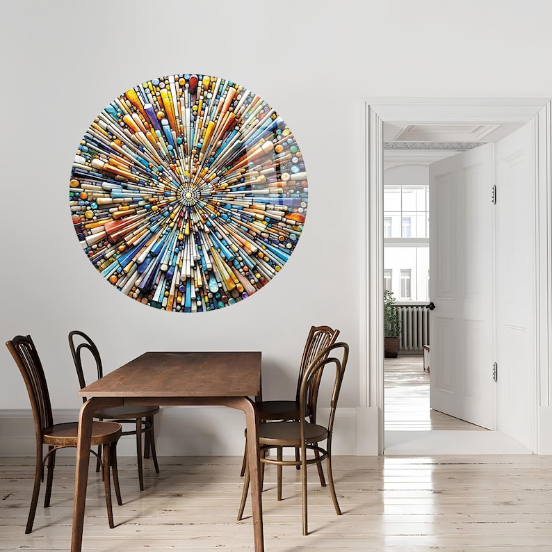 May include: A circular wall art piece with a colorful abstract design. The design features a variety of shapes and colors, including blue, yellow, orange, and white. The art piece is hanging on a white wall in a dining room setting.