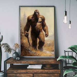May include: Framed art print featuring a detailed illustration of Bigfoot, a large, hairy, ape-like creature, walking through a mountainous landscape. The artwork is in warm, earthy tones, with a focus on the creature's fur and the natural environment.
