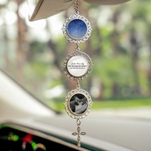May include: A silver car charm with three circular pendants. The top pendant displays a blue and white star map. The middle pendant has text that reads "Under this sky YOU BECAME MY DADDY June 18th 2020 Palo Alto, CA". The bottom pendant holds a black and white photo. A cross hangs at the bottom.