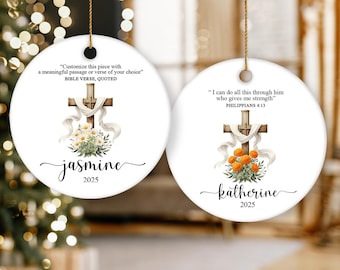 May include: Two white, round Christmas ornaments with gold string. Each ornament features a cross, floral arrangement, and text. One says "Jasmine 2025" and the other says "Katherine 2025".