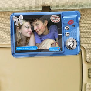 May include: A blue car visor mirror with a photo of a couple. The mirror has a digital camera design with buttons and a kiss mark. Text bubbles say "text me when you get home" and "I love you."