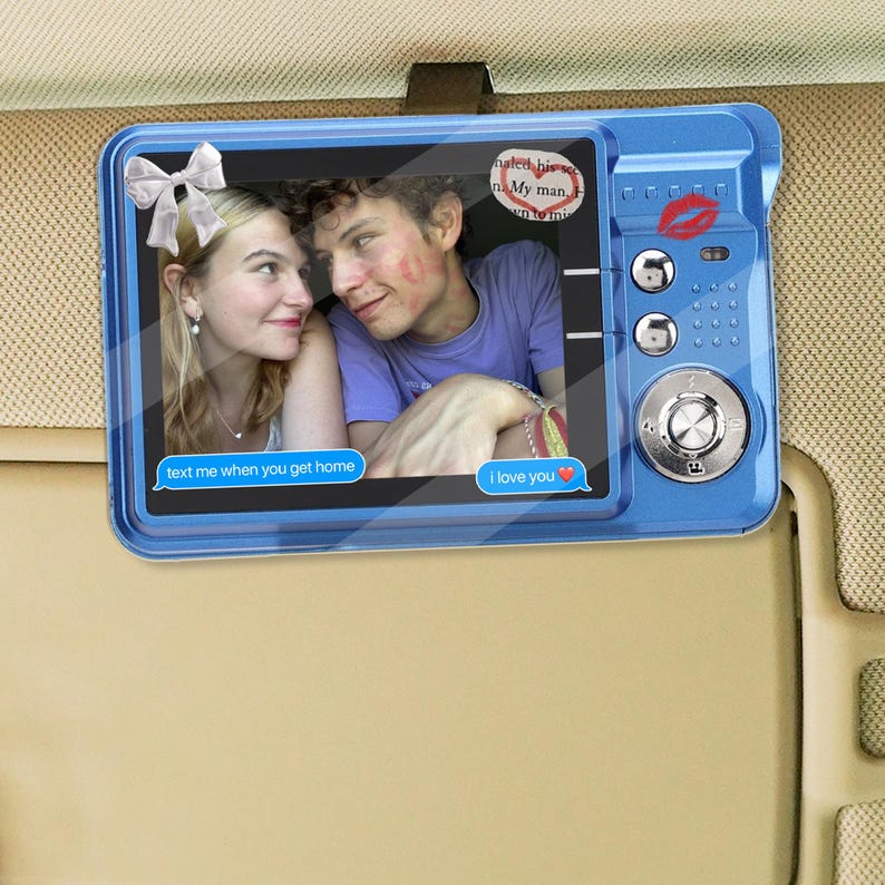 May include: A blue car visor mirror with a photo of a couple. The mirror has a digital camera design with buttons and a kiss mark. Text bubbles say "text me when you get home" and "I love you."