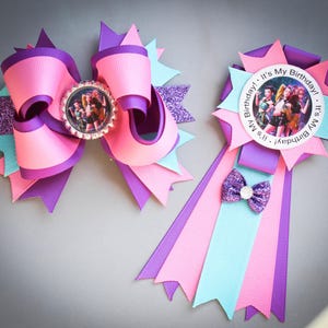 May include: Two handmade birthday accessories. One is a large pink, purple, and teal bow with a photo in the center. The other is a badge with a photo, ribbons, and a small bow. Both have the text "It's My Birthday!"