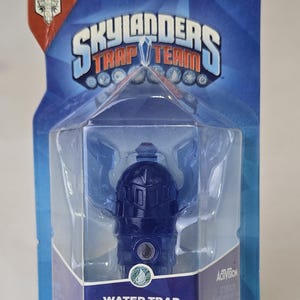 May include: A blue Skylanders Trap Team Water Trap toy figure in a plastic package. The package is blue and red and has the words "Skylanders Trap Team" and "Water Trap" on it. The figure is a blue and silver robot with a water drop symbol on its chest. The package is for ages 6 and up.