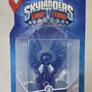 May include: A blue Skylanders Trap Team Water Trap toy in its packaging. The packaging is blue and red with the Skylanders Trap Team logo. The toy is a blue crystal with a water drop symbol on it. The packaging also says "6+ and Activision".