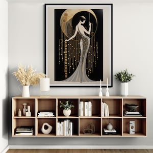May include: A framed wall art print featuring a stylised illustration of a person in a long, flowing gown standing before a large, golden crescent moon against a black background, accented with hanging gold geometric lines and circular motifs.