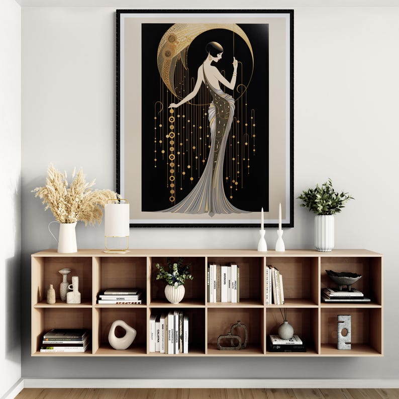 May include: A framed wall art print featuring a stylised illustration of a person in a long, flowing gown standing before a large, golden crescent moon against a black background, accented with hanging gold geometric lines and circular motifs.