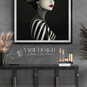 May include: A framed wall art print featuring a stylized illustration of a person wearing a wide-brimmed hat with black and white stripes, a matching striped high-neck garment, and bold red lipstick, set against a solid black background.