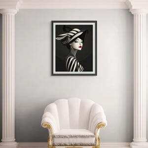 May include: A framed wall art print featuring a stylized portrait of a person wearing a wide-brimmed hat with black and white stripes. The subject has a high-collared striped garment, pale skin, dark eyeliner, and vibrant red lips against a dark background.