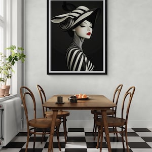 May include: A framed wall art print featuring a stylized portrait of a person wearing a wide-brimmed hat with black and white stripes. The subject has a striped neck and shoulders, closed eyes, and bright red lips against a dark background.